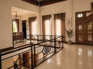 Un interior espacioso con una escalera de madera, un comedor y una puerta de madera decorativa.