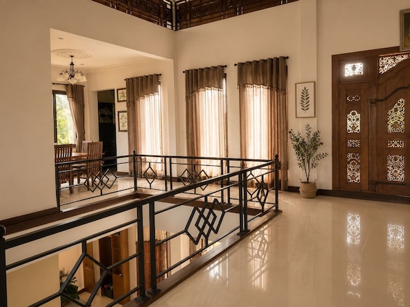 A spacious interior with a wooden staircase, a dining area, and a decorative wooden door.