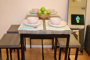A dining table with four white bowls, a basket of green apples, and chopsticks on a patterned placemat. - Stylish Studio on Roosevelt Row – Fast Wi-Fi (Phoenix)