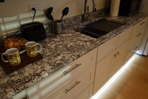 Una cucina con piani in granito, un tostapane, un lavello e una macchina per il caffè.