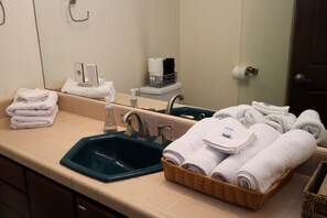 A bathroom with a sink, mirror, and a basket of towels. - Stylish Studio on Roosevelt Row – Fast Wi-Fi (Phoenix)