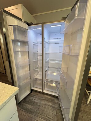 Eine moderne Küche mit Einbaukühlschrank, Holzboden und weißer Arbeitsplatte.