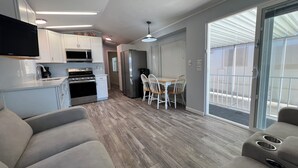 A modern kitchen with a microwave, stove, and refrigerator, a dining area with a table and chairs, and a sliding glass door leading to a balcony. - Relaxing 2 Bedroom with Panoramic Lake View from inside and out (Lake Havasu City)