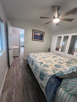 Ein Schlafzimmer mit Bett, Deckenventilator, gerahmtem Bild und Kleiderschrank.