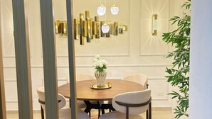 Un espace repas comprenant une table ronde, des chaises, un vase de fleurs, un mur décoratif et un luminaire suspendu.