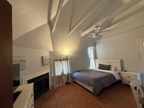 Una camera da letto con un letto, comodini, una cassettiera, un camino e una ventola a soffitto.