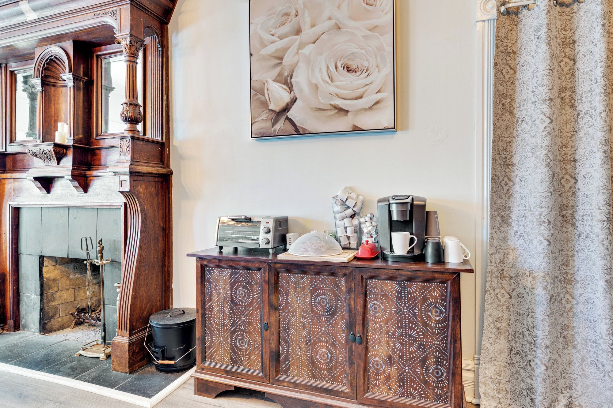 A room with a fireplace, a coffee station, and a decorative cabinet.