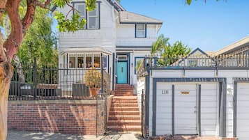 A two-story house with a garage, a blue door, and a brick staircase leading to the entrance.