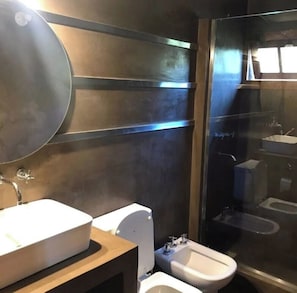 Moderni kylpyhuone, jossa on suuri peili, wc-istuin, bidee ja pesuallas.