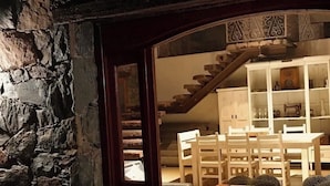 Eine Steinsäule, eine Holztreppe und ein Essbereich mit weißer Möbel.