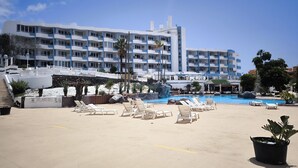 Un complexe hôtelier doté d’une piscine, de chaises longues et d’un immeuble à plusieurs étages avec des balcons.