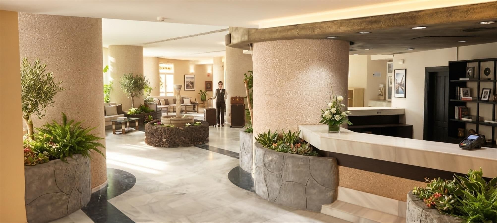Eine Hotelhalle mit Empfangstresen, einer Sitzecke und einem Brunnen.
