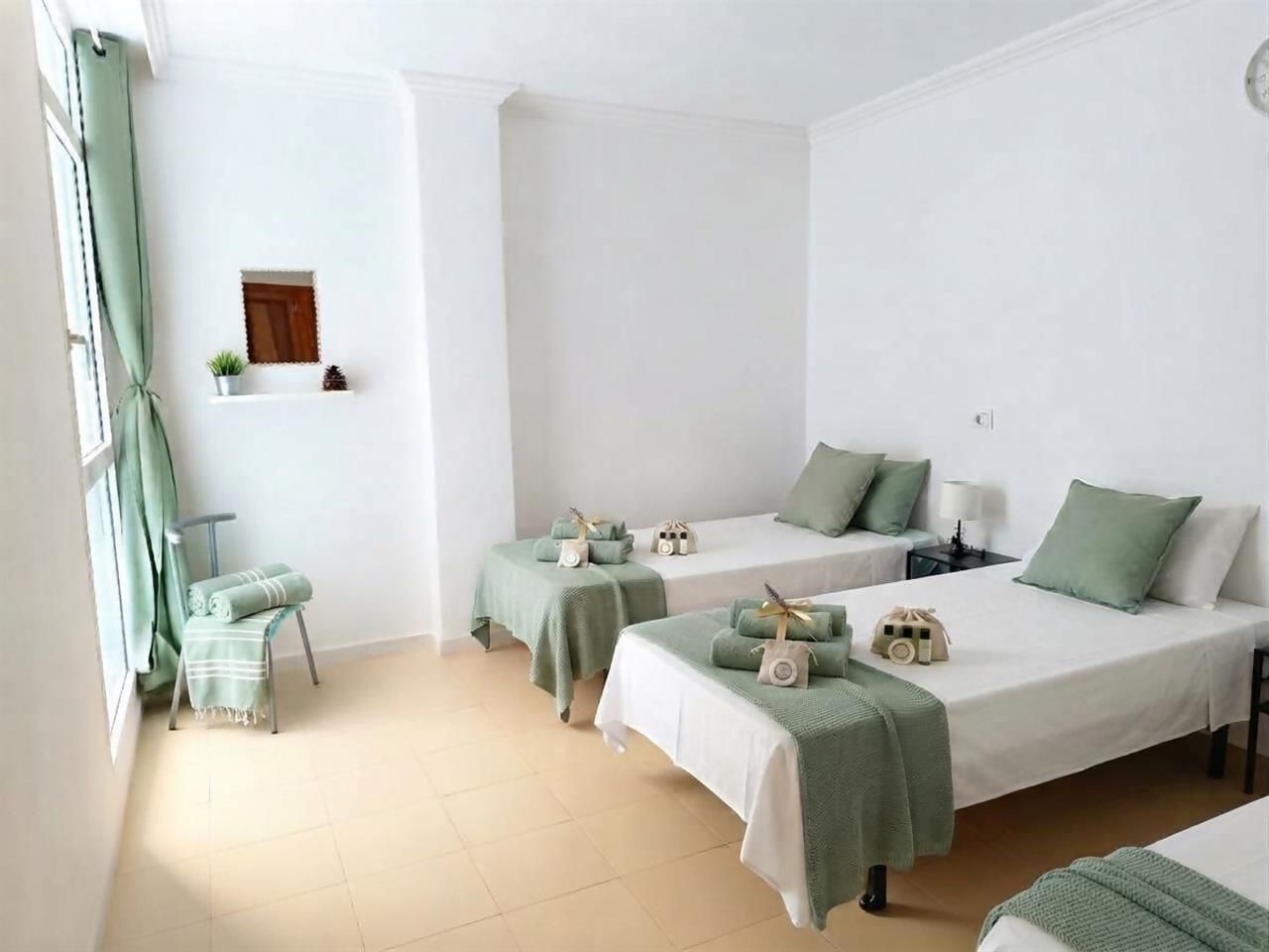 Une chambre avec deux lits, une petite table, une chaise et une fenêtre avec des rideaux.