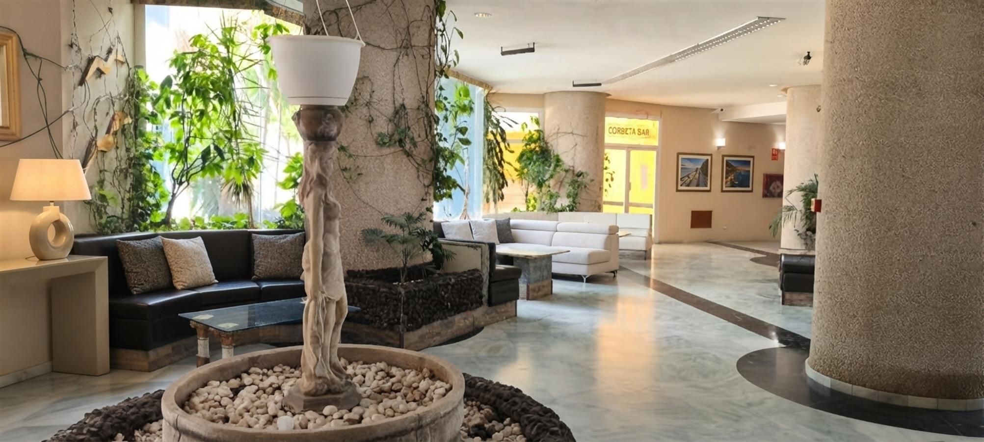 A lobby with a central water feature, seating areas, and a reception desk.