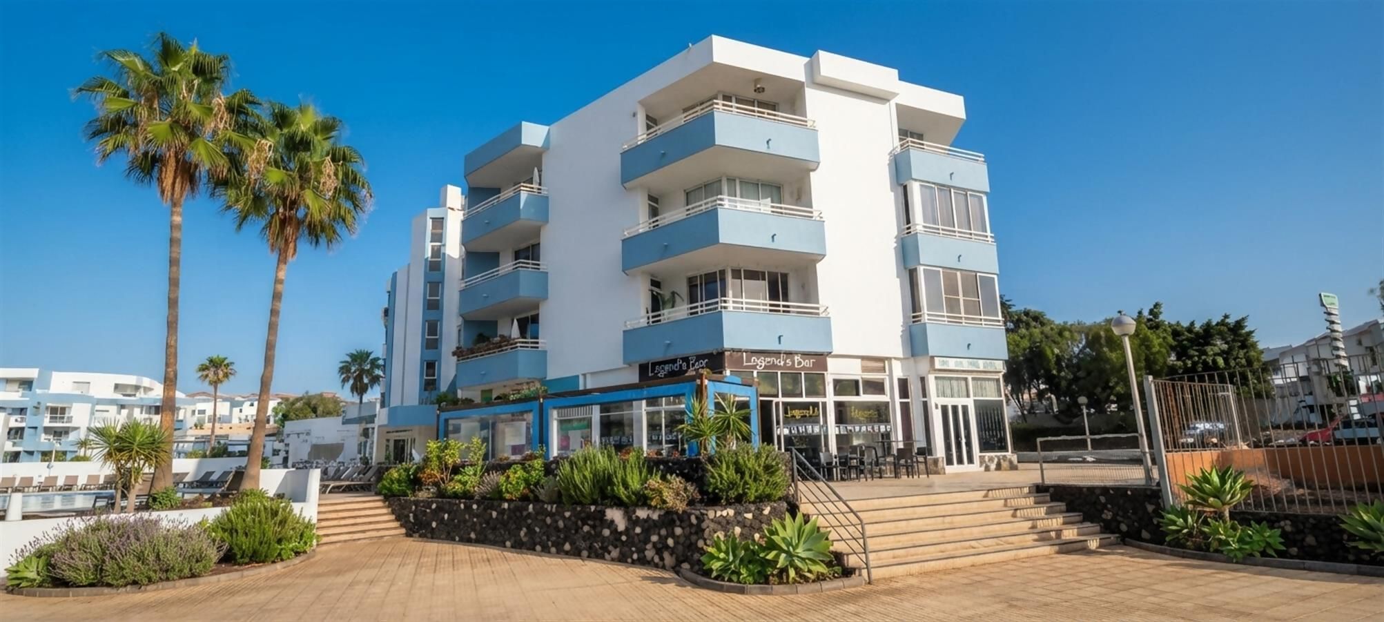 A multi-story hotel with balconies, a bar, and a pool area.