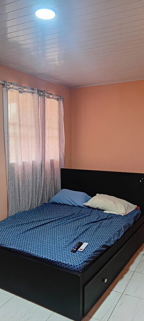 A bedroom with a bed, curtains, and a ceiling light. - Downtown 2-story Tiny House (Granada)