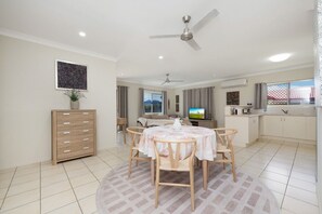A modern living room with a dining area, a TV, and a kitchen. - Sweet Retreat Rosslea (Rosslea)