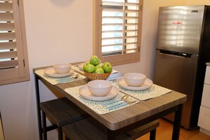 A kitchen with a dining table set for four, a refrigerator, and a window with blinds. - Downtown Phoenix Studio – Walk to Arts & Dining (Phoenix)