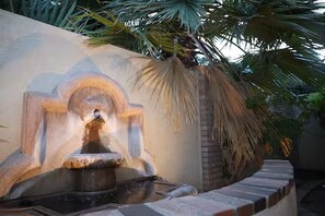A stone fountain with water spouting from a central point, surrounded by a low brick wall and palm trees. - Downtown Phoenix Studio – Walk to Arts & Dining (Phoenix)