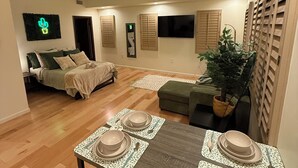 A dining area with a table set for four, a ceiling fan, and a television in the background. - Downtown Phoenix Studio – Walk to Arts & Dining (Phoenix)