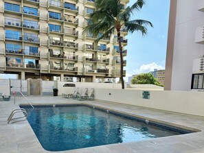 Un hôtel doté d’une piscine, de plusieurs balcons et d’un palmier.