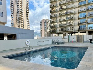 Ein Pool auf dem Dach mit Blick auf hohe Gebäude, einem Rettungsring und einem verschlossenen Eingang.