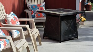 Espace extérieur aménagé avec des chaises et une table, un mur rouge et des plantes en pot.
