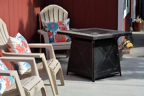 Terrasse mit Stühlen, einem Tisch, einer roten Wand und Topfpflanzen.