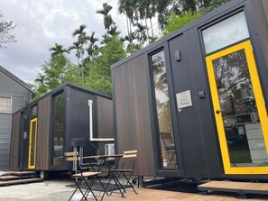 Een rij modulaire cabins met buitendeuren, een tafeltje met stoelen en een raam.