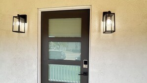 A modern door with a frosted glass panel, a small window, and two wall-mounted lights.