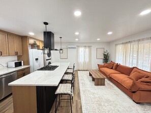 A modern kitchen with a central island, wooden cabinets, and a built-in stove. - 洛杉矶pomona全新装修独立屋｜2房2卫三床（含高低床）｜室内洗烘｜免费停车｜最多4人｜精致原木风 (Pomona)