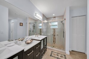 A modern bathroom with a glass-enclosed shower, a large mirror, and a vanity with a bowl sink.
