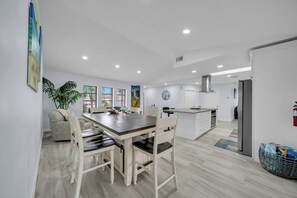 A modern kitchen with a dining area, white cabinetry, and a large island.