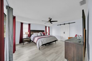 A bedroom with a bed, a desk, a ceiling fan, and a wardrobe.