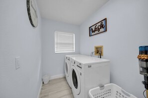 A laundry room with a washing machine, dryer, and a wall-mounted sign.