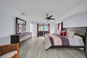 A bedroom with a bed, dresser, and a ceiling fan.