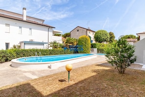 A residential area with a swimming pool, a small garden, and a building with a blue garage door. - # residence Francesca°# swimming pool* (Jesolo)