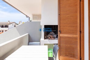 A balcony with a white table, a green trash bin, and a wooden door. - # residence Francesca°# swimming pool* (Jesolo)