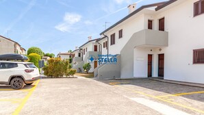 En bostadsgata med vita byggnader, en vit bil och en tydligt synlig logotyp: ”immobiliare STELLA”.