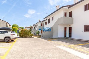 Calle residencial con edificios blancos, un coche blanco y el logo visible 'immobiliare STELLA'.