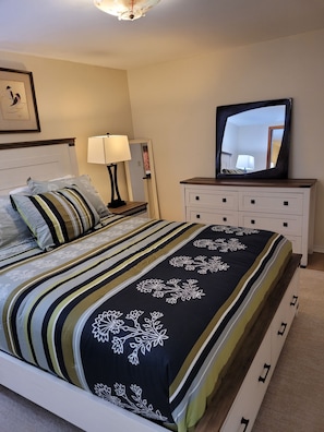 Un dormitorio ordenado con cama, mesitas de noche, un espejo y un aparador.