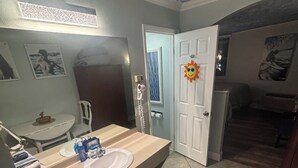 A bathroom with a sink, mirror, towel rack, and a shower area. - COSTAL GETAWAY ON CLEARWATER BEACH (Clearwater)