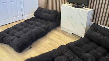A room with a sofa bed, a television on a cabinet, and a striped wall.