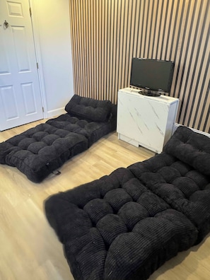 A room with a sofa bed, a television on a cabinet, and a striped wall. - Super Cool Loft 
Can Sleep Four (Toronto)