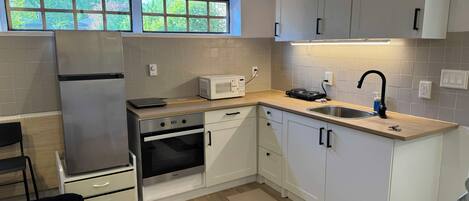 A modern kitchen with white cabinets, a stainless steel refrigerator, a microwave, a dishwasher, and a sink with a faucet.