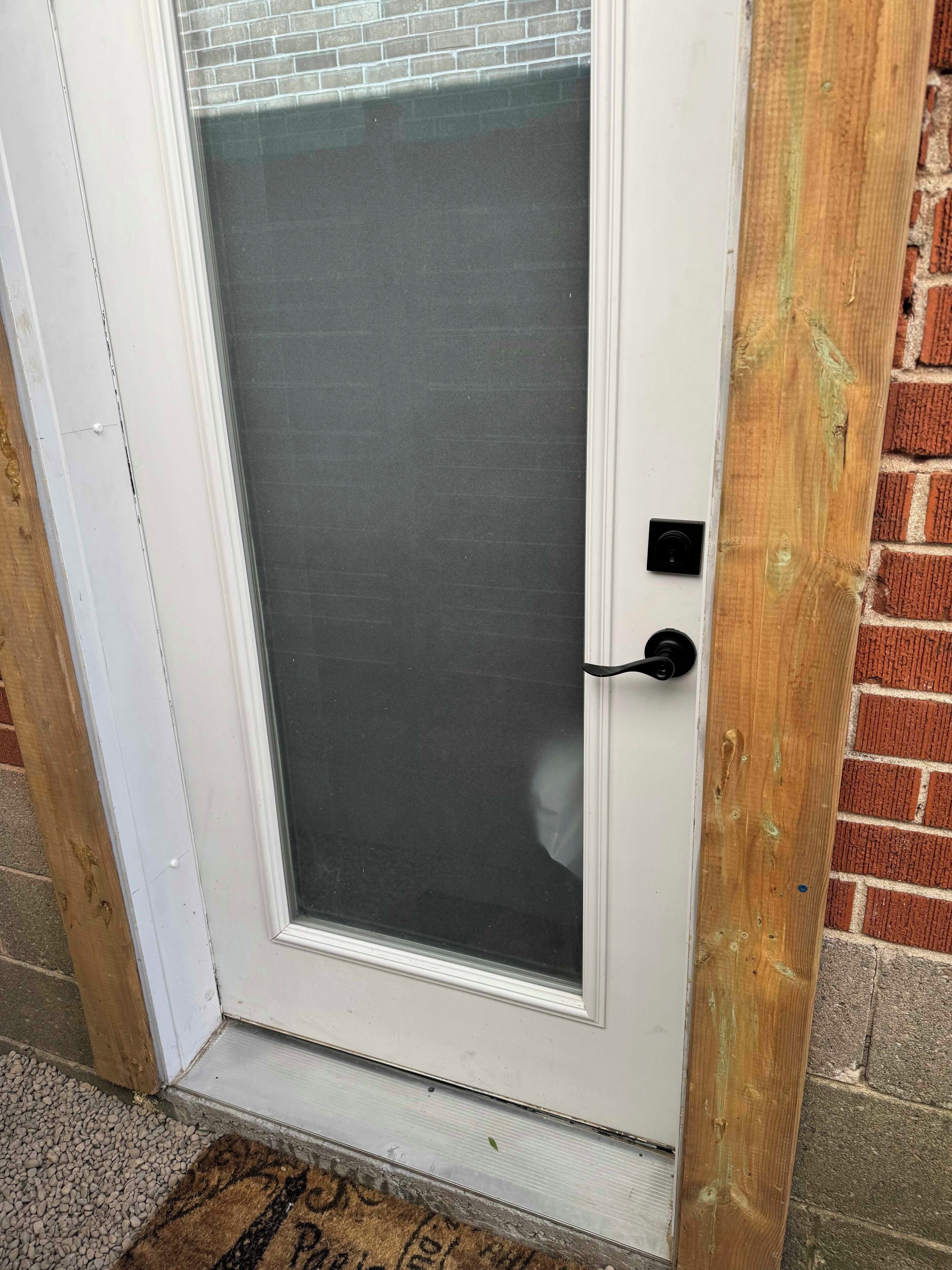 A white door with a glass panel, a black handle, and a small black lock.