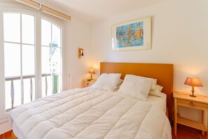 Ein Schlafzimmer mit einem großen Bett, einem Nachttisch mit Lampe, einem Fenster mit Blick und einem Bild an der Wand.