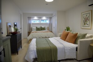 Ein Schlafzimmer mit zwei Betten, einem Schminktisch, einem Stuhl und einem Fenster mit Vorhängen.