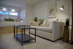 Ein modernes Wohnzimmer mit Sofa, Couchtisch, Lampe und einem gerahmten Bild an der Wand.