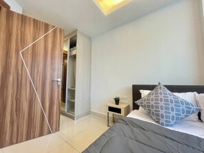 A bedroom with a bed, bedside table, and a wardrobe. - Room-stylish 1BR Garden View at Laguna B (Pattaya)